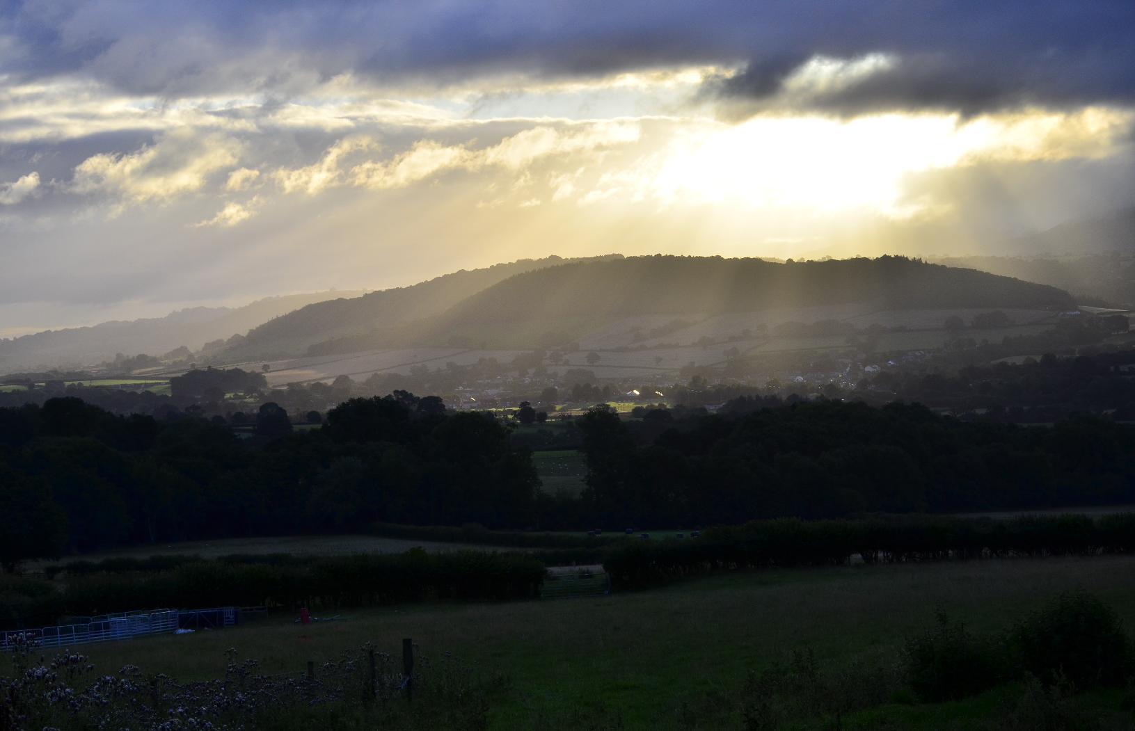 Rays shining through clouds onto a hilly landscape