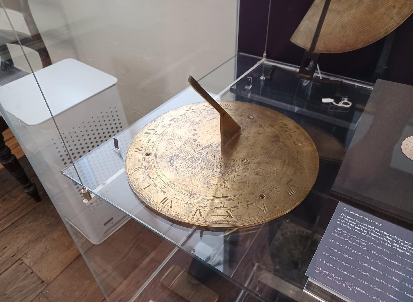 A brass sundial in a glass display